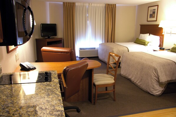 Une chambre d’hôtel équipée d’un lit, d’un bureau avec une chaise, d’une télévision et d’un appareil de climatisation.