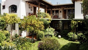 Una casa de dos pisos con un porche cubierto y un jardín exuberante.