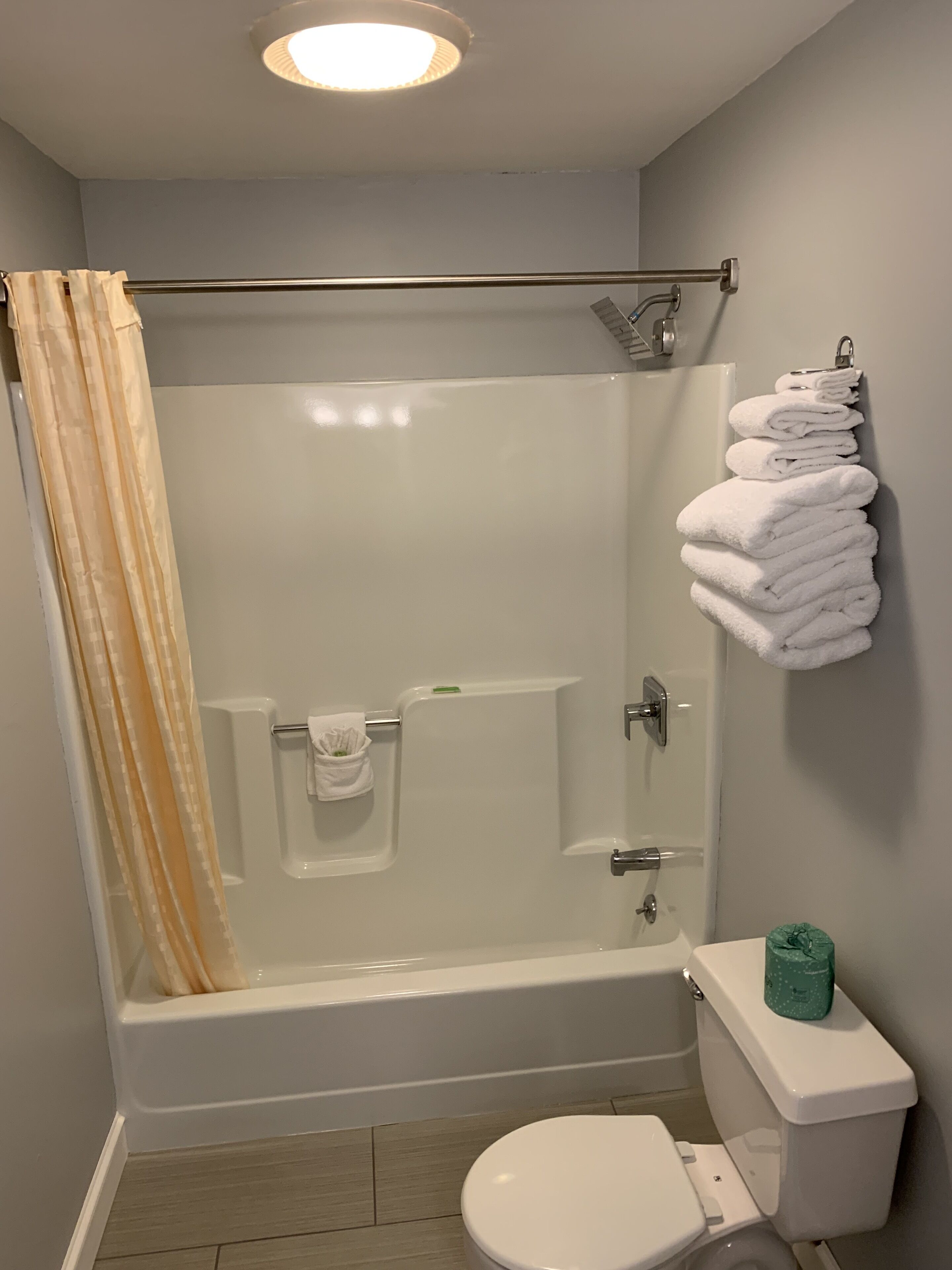 A bathroom with a glass-enclosed shower, a toilet, and a towel rack with folded towels.