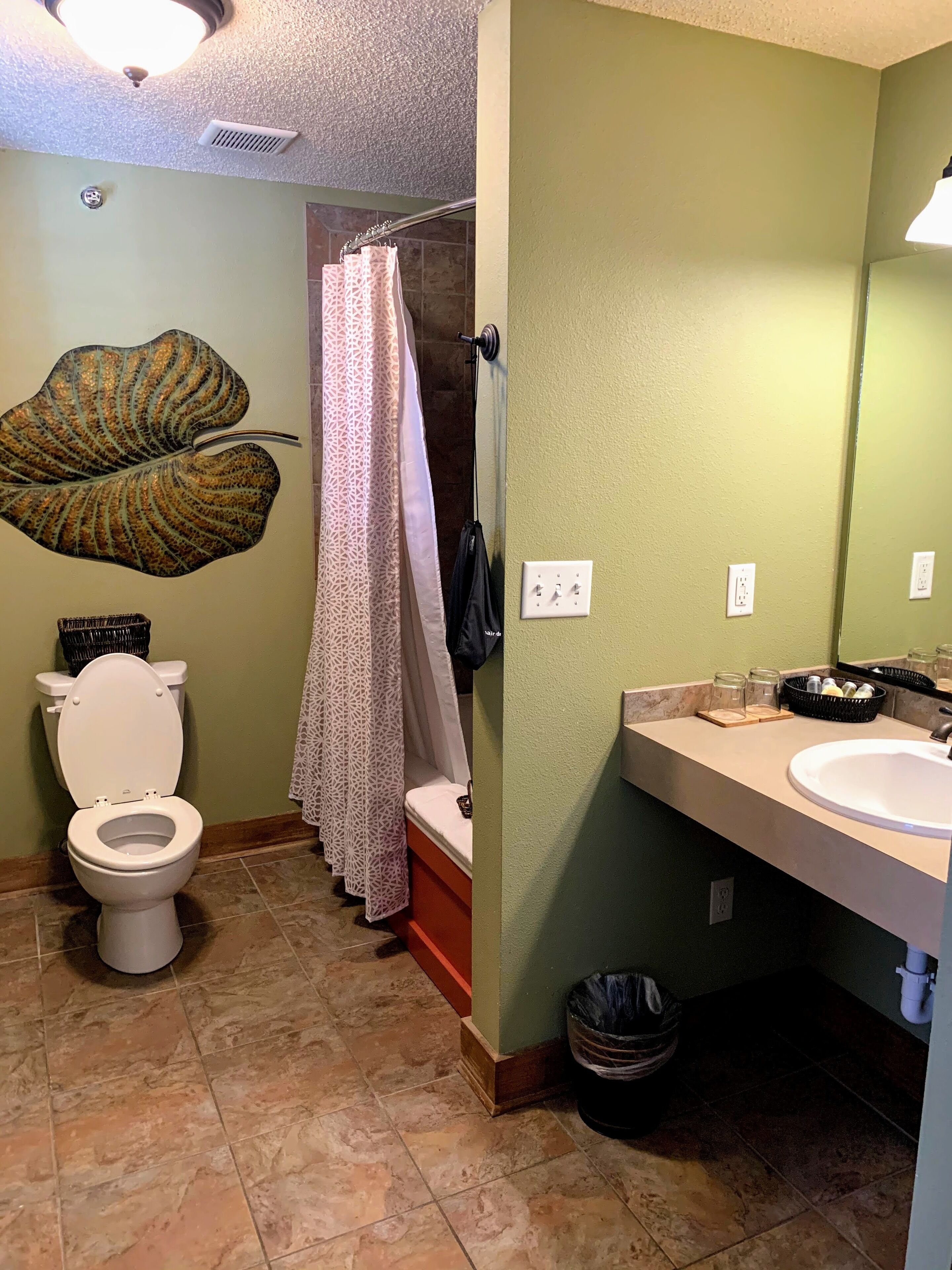 A bathroom with a toilet, shower, and sink.