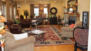 A spacious living room with a fireplace, leather sofas, a coffee table, and a large clock on the wall. - Iowa House (Ames)