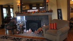 A cozy living room with a fireplace, a sign reading "Be our Guest," and a "WELCOME" sign. - Iowa House (Ames)