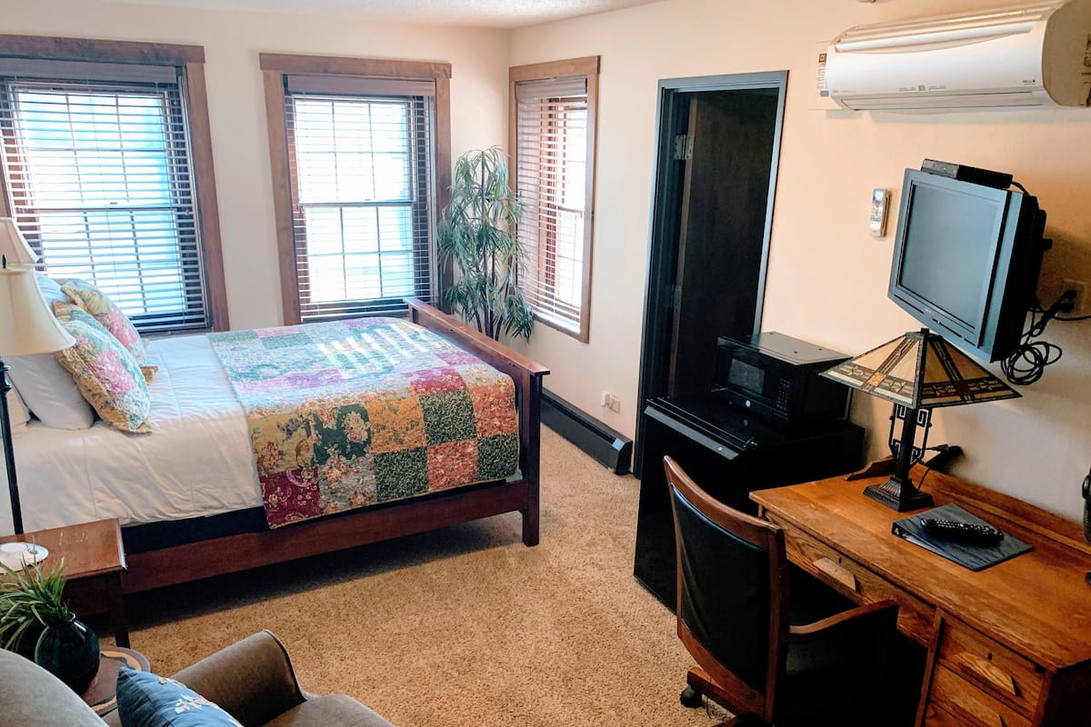 Un dormitorio con una cama, un escritorio, una silla y un televisor.