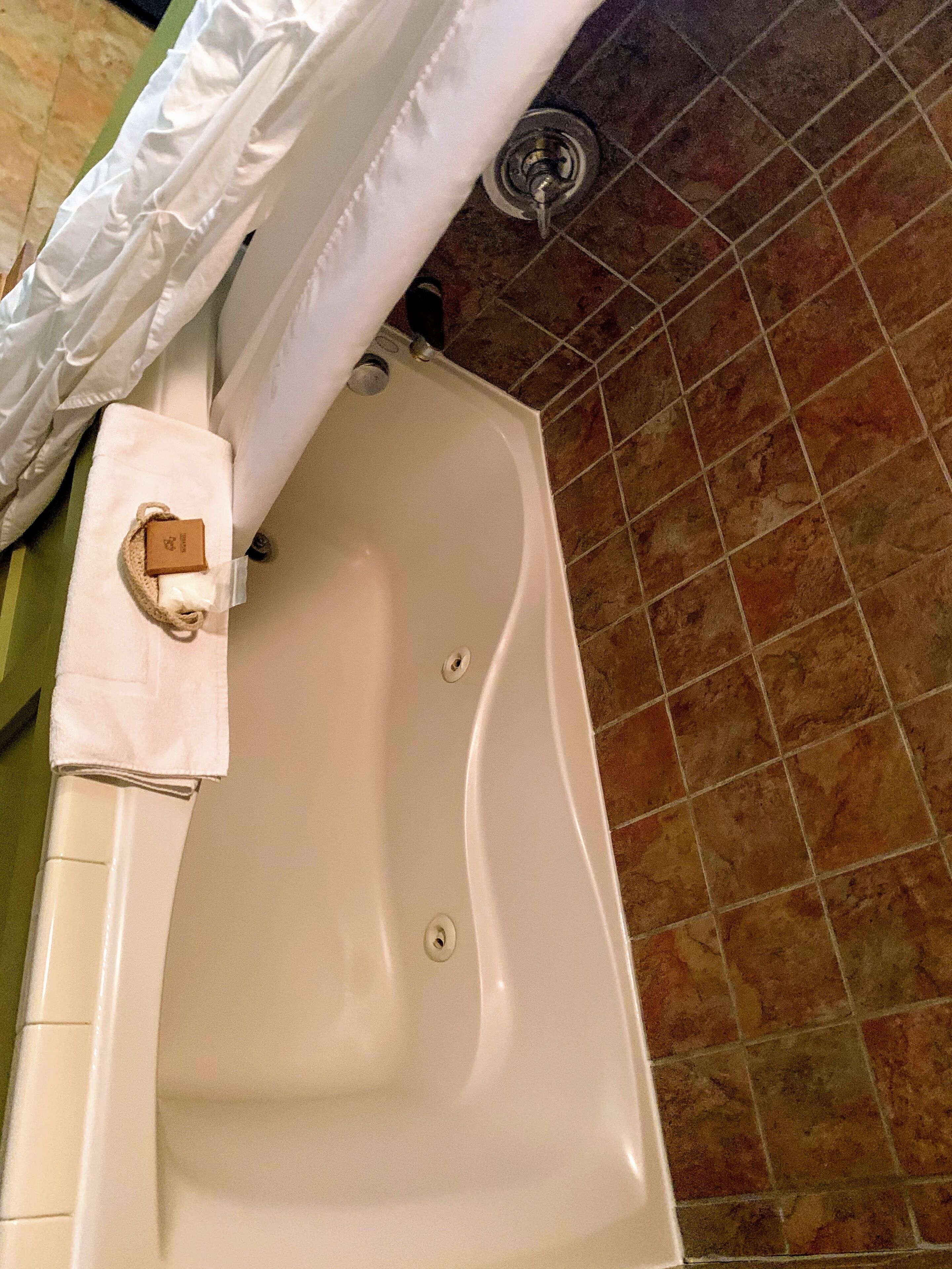 Una bañera con una toalla y una botella al lado.