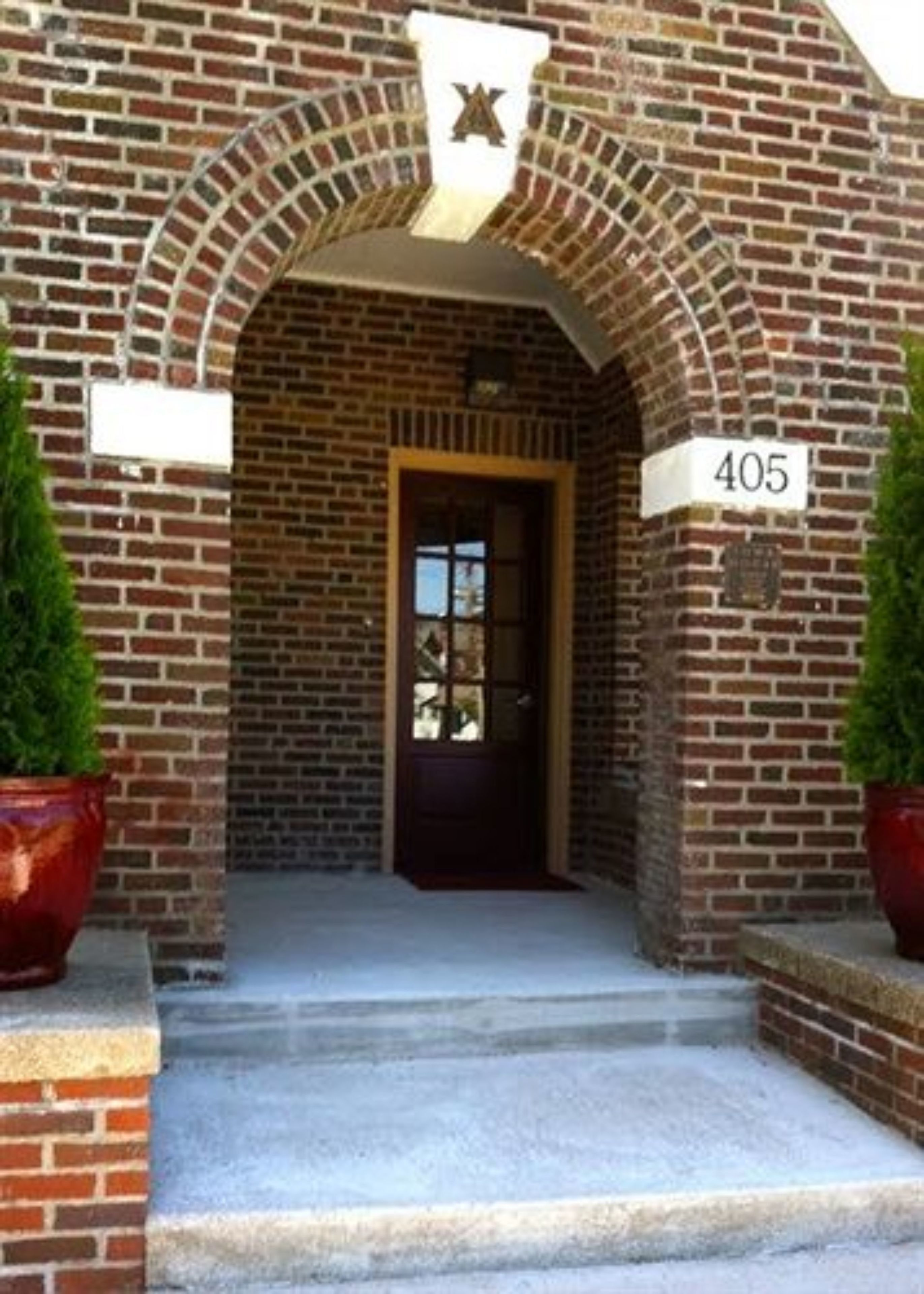 A brick building with a large arched entrance, a door, and a number sign '405'.