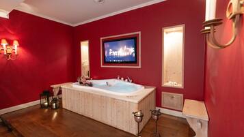 Relax in a spacious bathroom with a bathtub, television, and comfortable seating.