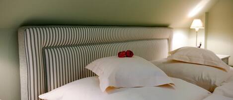 A bed with striped headboard and white pillows, a bedside lamp, and a green wall.