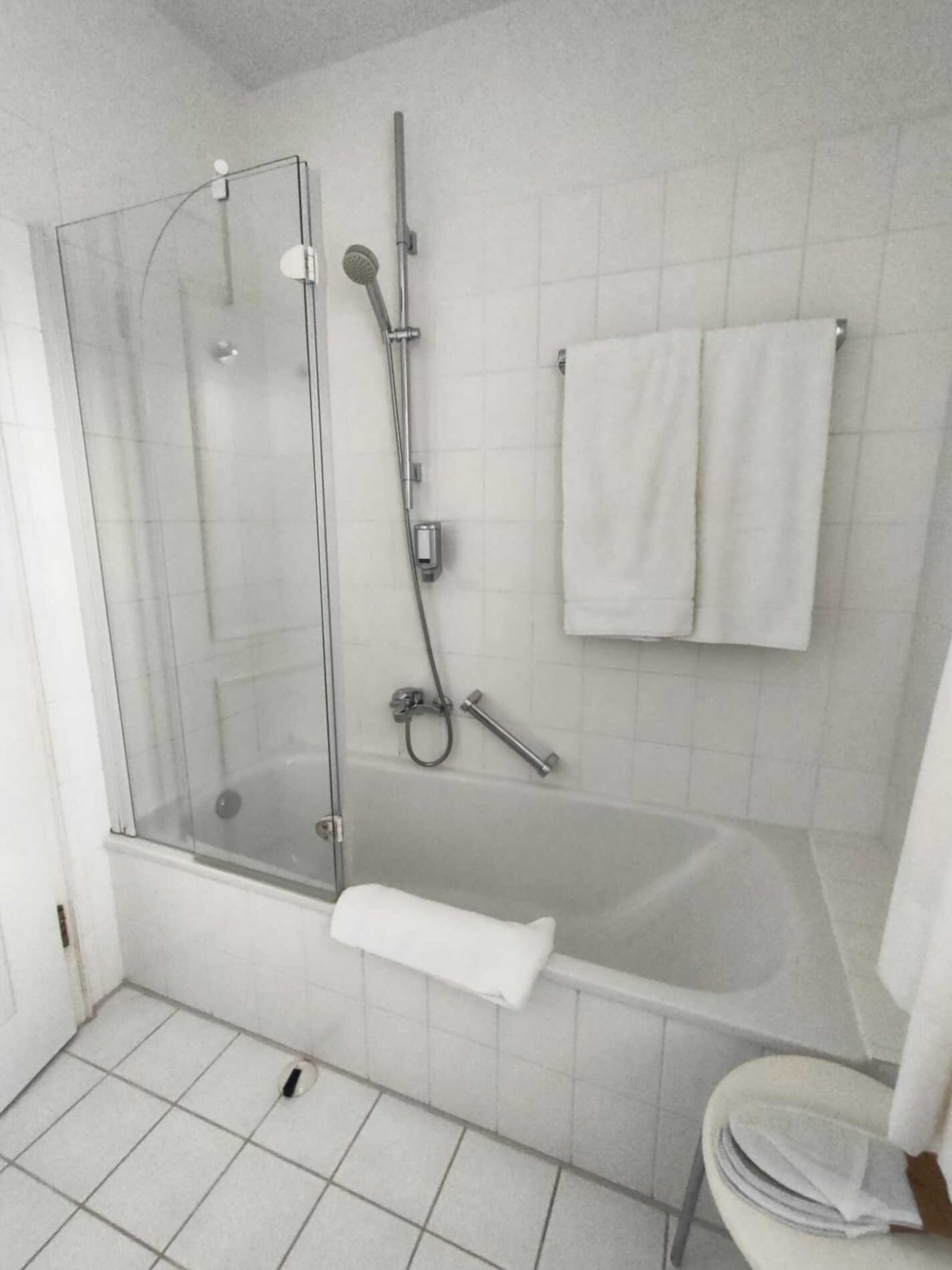 A modern bathroom with a glass-enclosed shower, a bathtub, and a toilet.