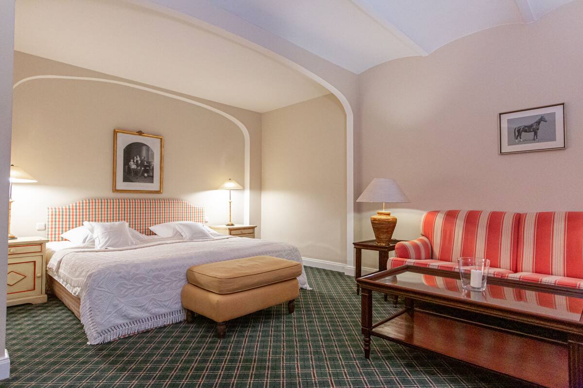 Una habitación de hotel con cama, sofá, mesa y lámpara.