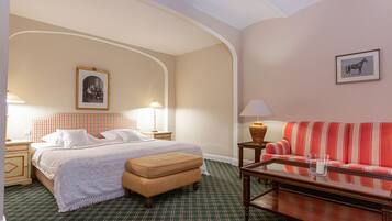 Una habitación de hotel con cama, sofá, mesa y lámpara.