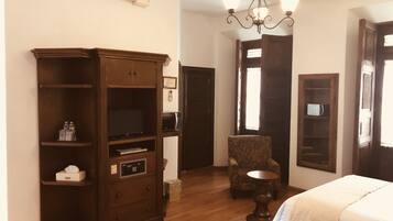 Una habitación de hotel con un armario de madera, una silla, una mesita redonda y una cama.