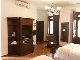 Una habitación de hotel con un armario de madera, una silla, una mesita redonda y una cama.