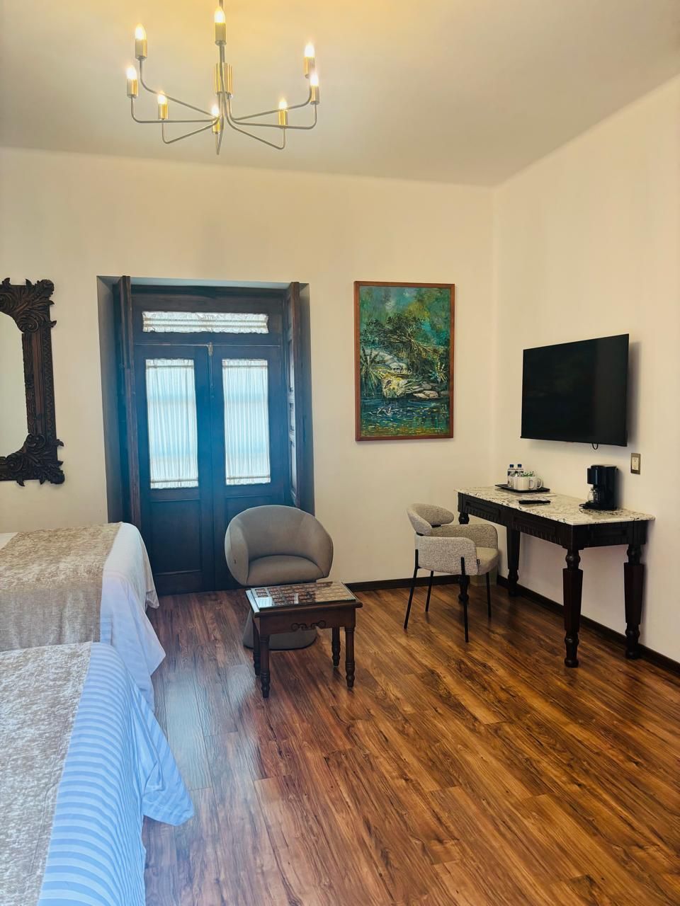 Une chambre d’hôtel avec un lit, un bureau et une chaise, une télévision et un tableau au mur.