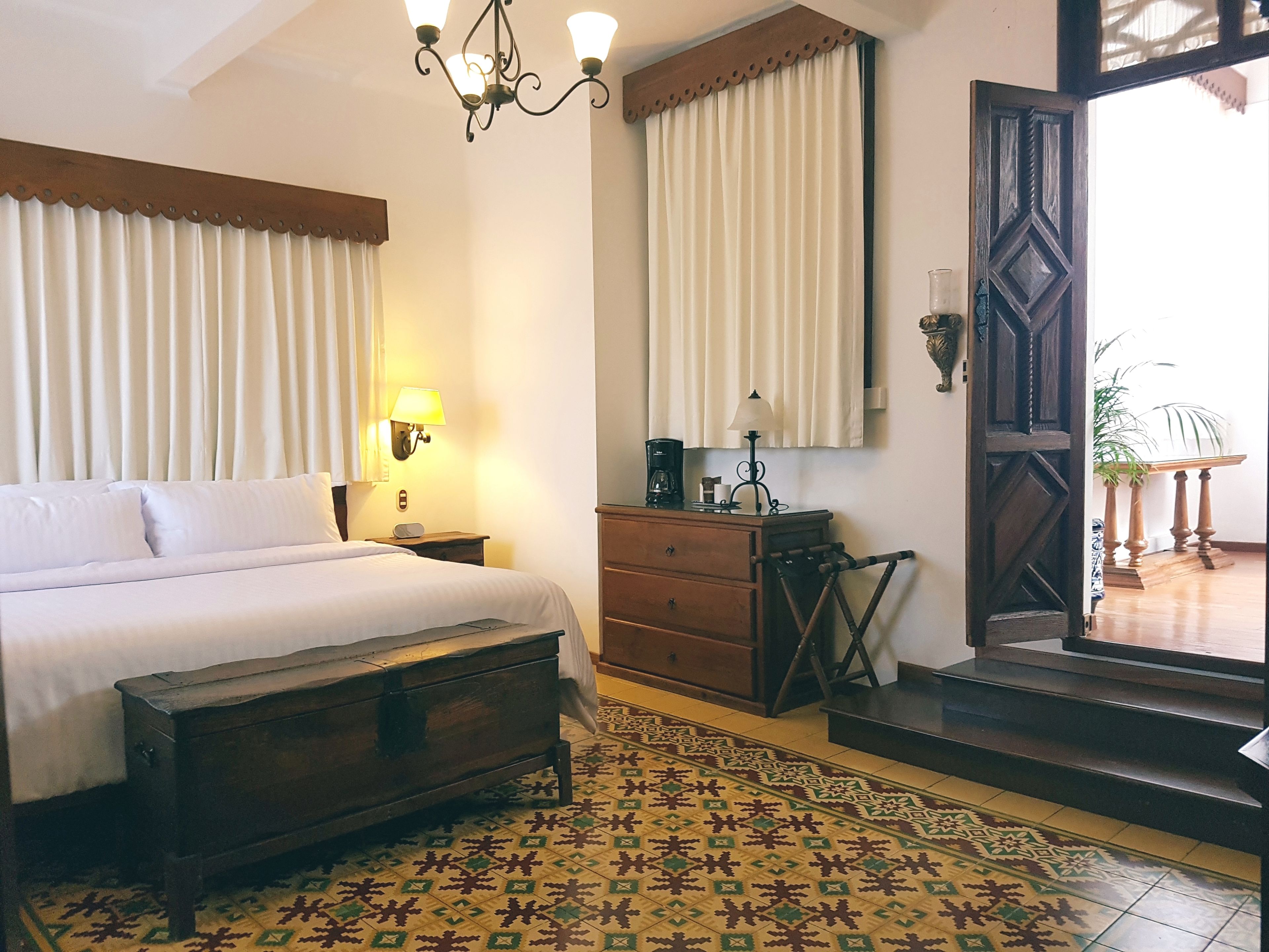 A bedroom with a bed, nightstand, dresser, and a patterned rug.