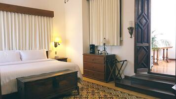 A bedroom with a bed, nightstand, dresser, and a patterned rug.