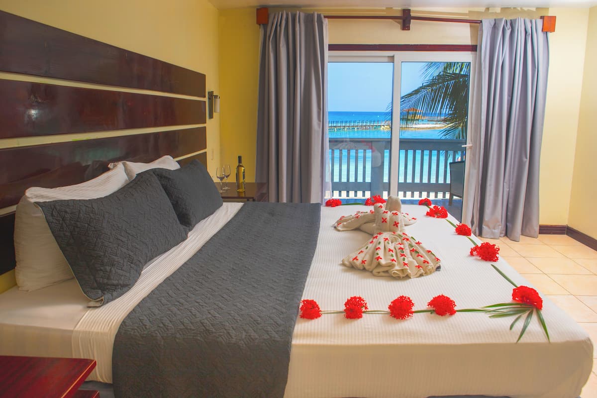 A neatly made bed with a white and gray bedspread, a wooden headboard, and red flowers on the bed.