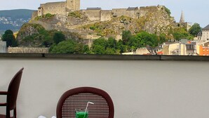 A table with a hat, glasses, and a menu, overlooking a historic castle. - Hotel Florida (Lourdes)