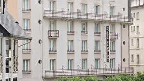 A multi-story hotel with balconies, a sign indicating it is a hotel, and a parking area in front. - Hotel Florida (Lourdes)