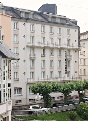 A multi-story hotel with balconies, a sign indicating it is a hotel, and a parking area in front. - Hotel Florida (Lourdes)