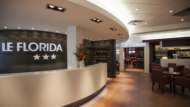 A reception area with a 'LE FLORIDA' sign, a bar, and a restaurant. - Hotel Florida (Lourdes)