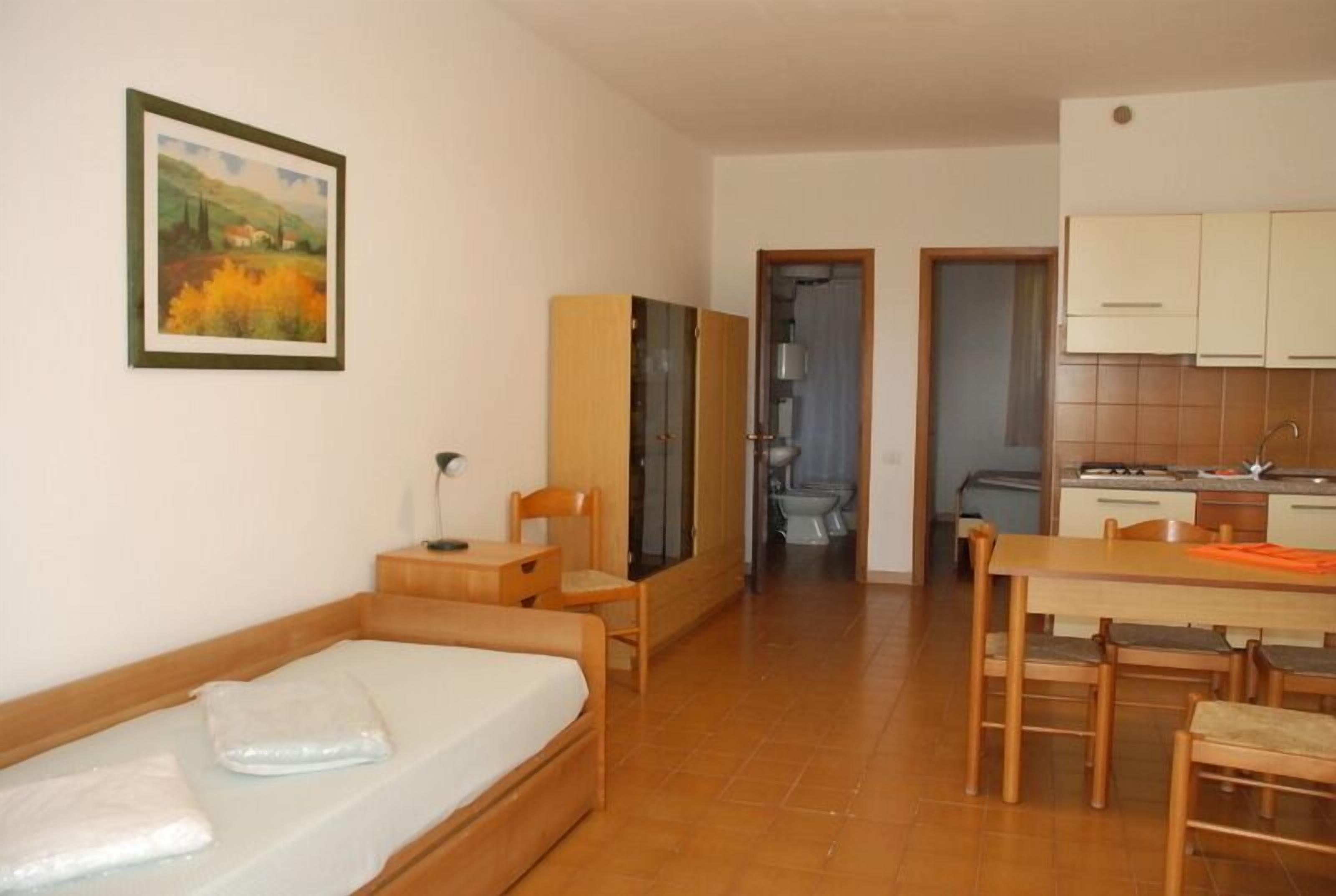 Una stanza accogliente e arredata con un letto, un tavolo di legno e una sedia. Presente un quadro appeso alla parete e una porta che conduce al bagno.