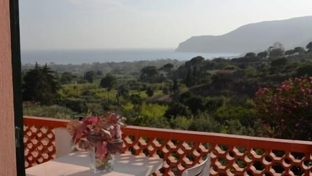 A balcony with a table and chairs, overlooking a mountainous landscape and the sea. - Appartamenti Elbamar Lacona (Capoliveri)