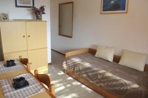 Un petit logement composé d’une seule pièce, comprenant un lit, une table avec une chaise et un placard.