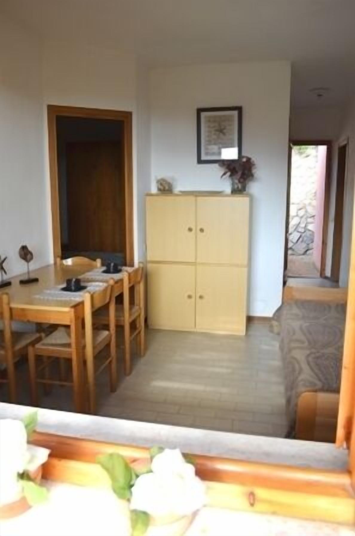 Un coin repas avec une table et des chaises en bois, un buffet de couleur crème et un tableau encadré au mur.