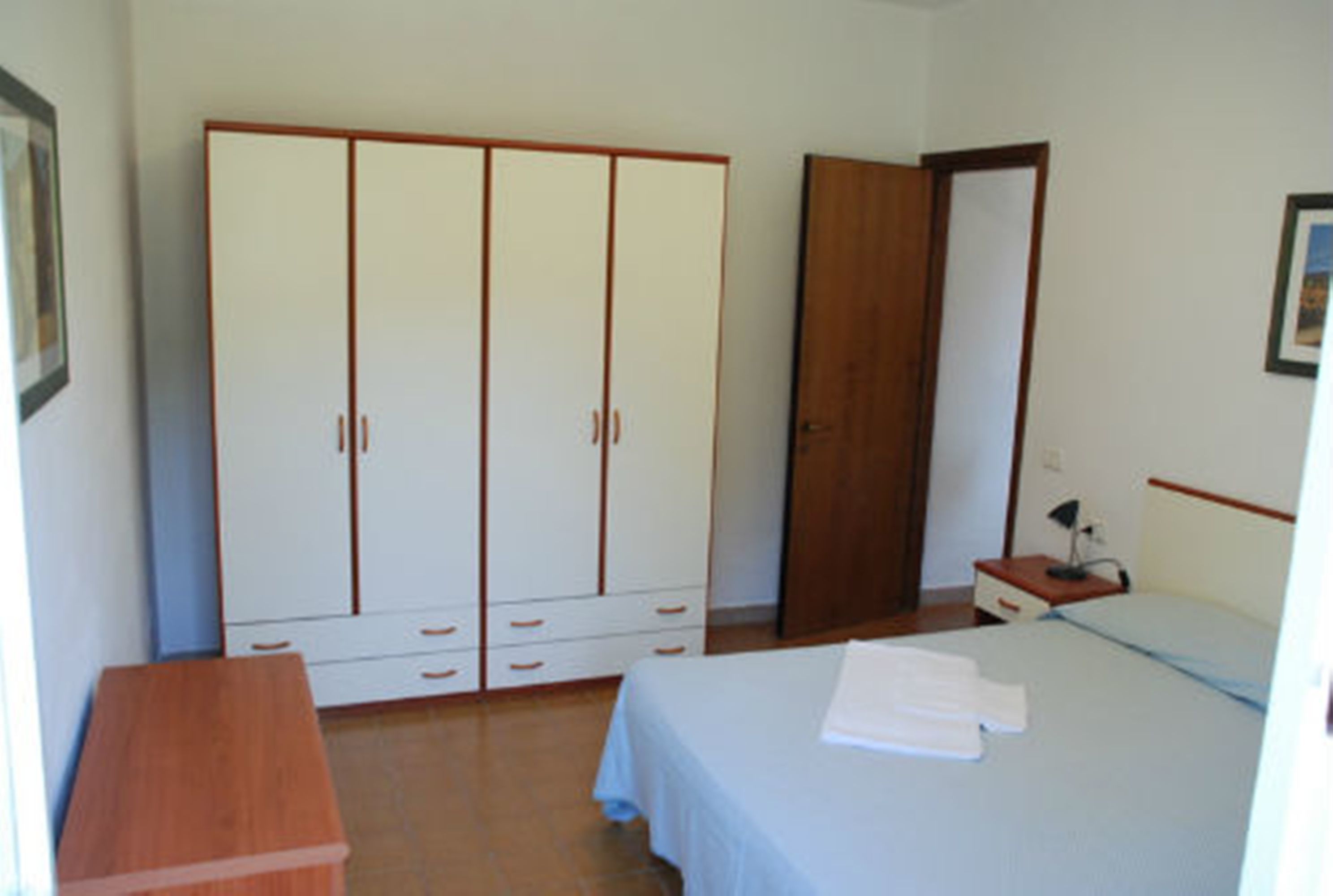 Quarto com cama, guarda-roupa, mesa de cabeceira e espelho.