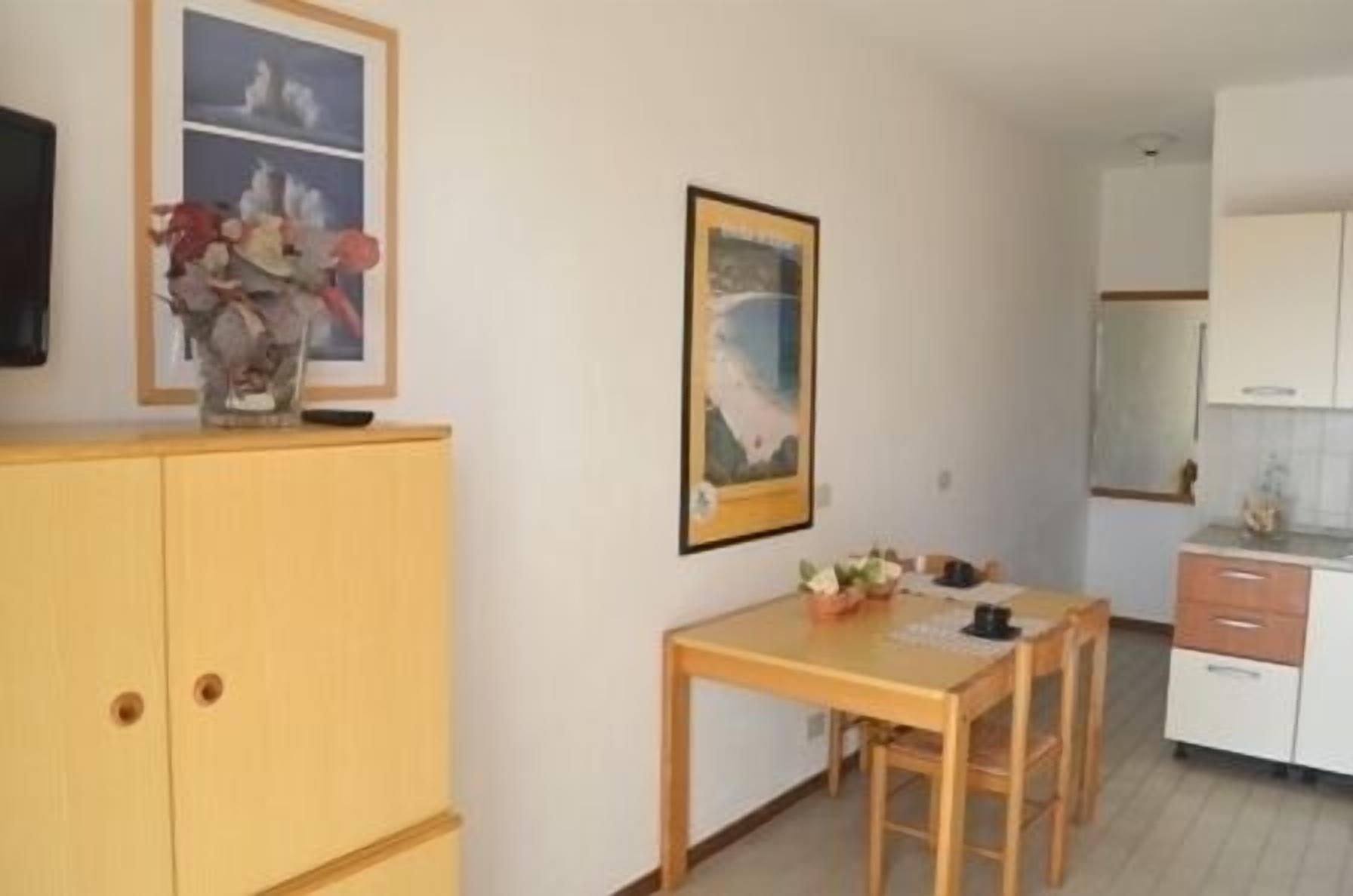 A small, clean room with a wooden table and chairs, a cabinet, and a framed picture on the wall.