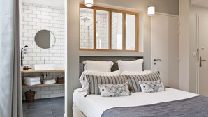 A modern bedroom with a large bed, a bedside table, a mirror, and a window. - Hôtel Les Costans, The Originals Relais (Perros-Guirec)