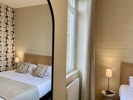 Una habitación de hotel con una cama, una mesita de noche con lámpara y una ventana con cortinas.