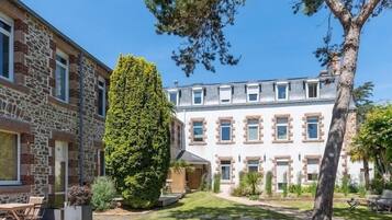 A two-story building with stone and white facades, a well-maintained lawn, and outdoor seating.