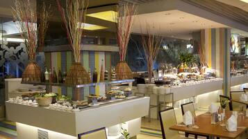 A modern restaurant with a buffet setup, featuring a variety of dishes and decorative elements like tall, slender vases with branches.