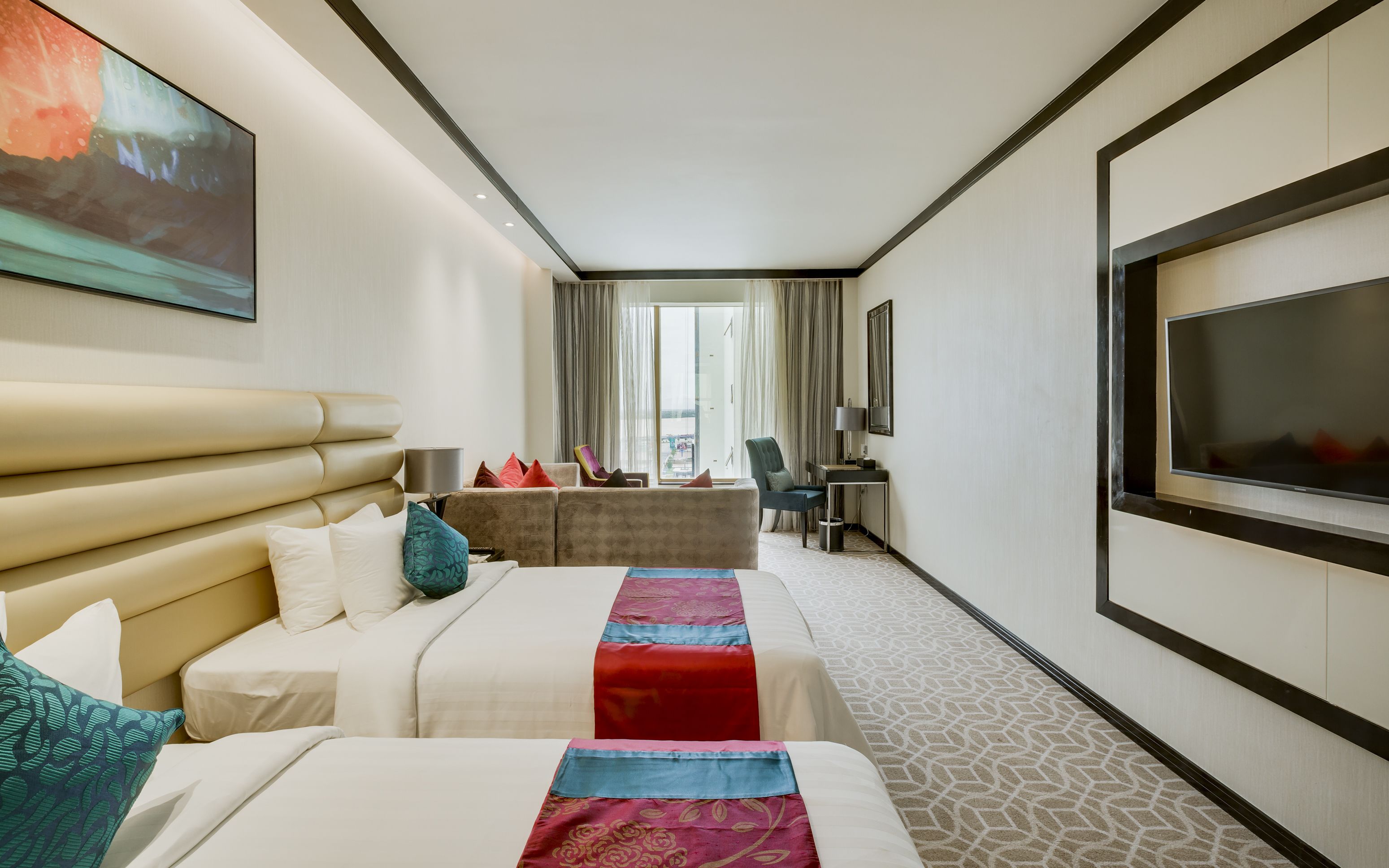 A hotel room with a large bed, a sofa, a desk, and a television.
