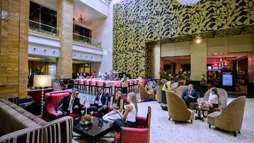 Eine geräumige Lobby mit mehreren Sitzbereichen, einer zentralen Bar und einer dekorativen Decke.