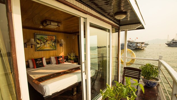 Una habitación con cama, un cuadro y vistas a barcos en el agua.