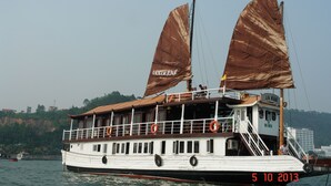 Un barco grande con dos velas grandes, cubierta con barandillas y boyas salvavidas.