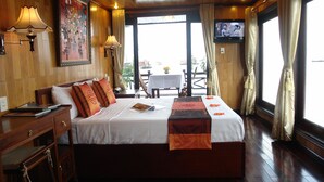 Una habitación de hotel con una cama grande, paredes de madera, una mesa de comedor con sillas y un televisor en la pared.
