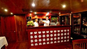 Un área de bar con paneles de madera, una barra con un panel trasero estampado y un barista preparando una bebida.