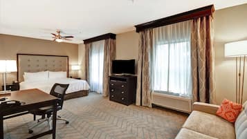 Una habitación de hotel con cama, escritorio, silla, televisor y sofá.
