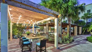 Ein Terrassenbereich im Freien mit einer Holzpergola, Sitzgelegenheiten und einer Bar.