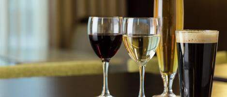 Four glasses of different beverages on a wooden table.