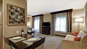 Ein Hotelzimmer mit Essbereich, einer Couch, einem Fernseher und einem Bild an der Wand.
