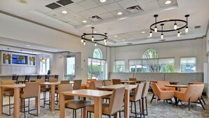 A spacious dining area with multiple tables and chairs, large windows, and a modern chandelier. - Homewood Suites by Hilton Lake Buena Vista - Orlando (Orlando)