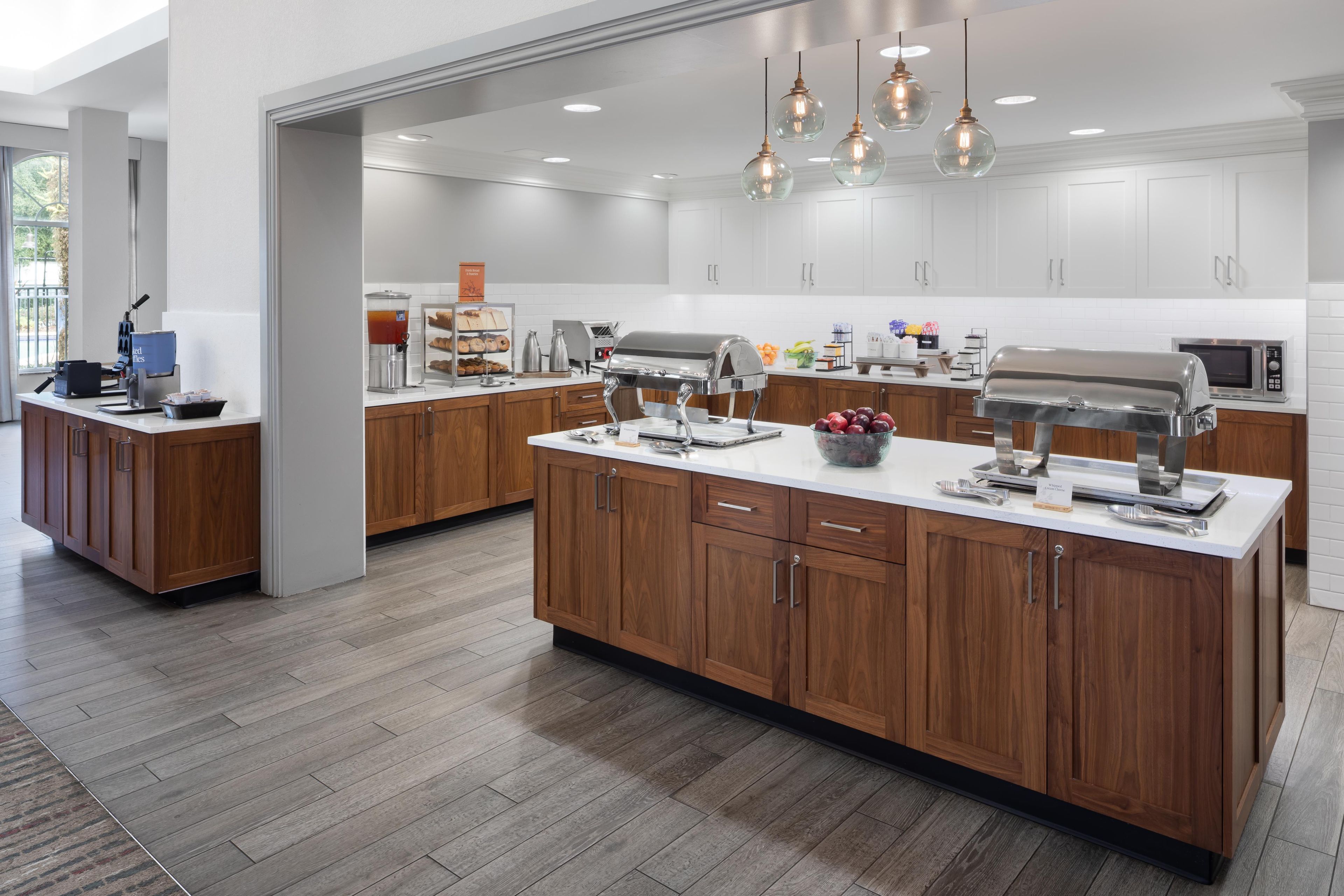 A modern kitchen with wooden cabinets, a central island, and various appliances.