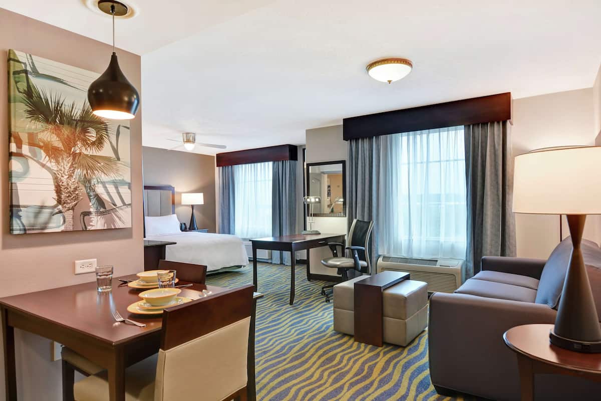 Une chambre d’hôtel comprenant un lit, un bureau, un canapé, une chaise et un coin repas avec une table et des chaises.