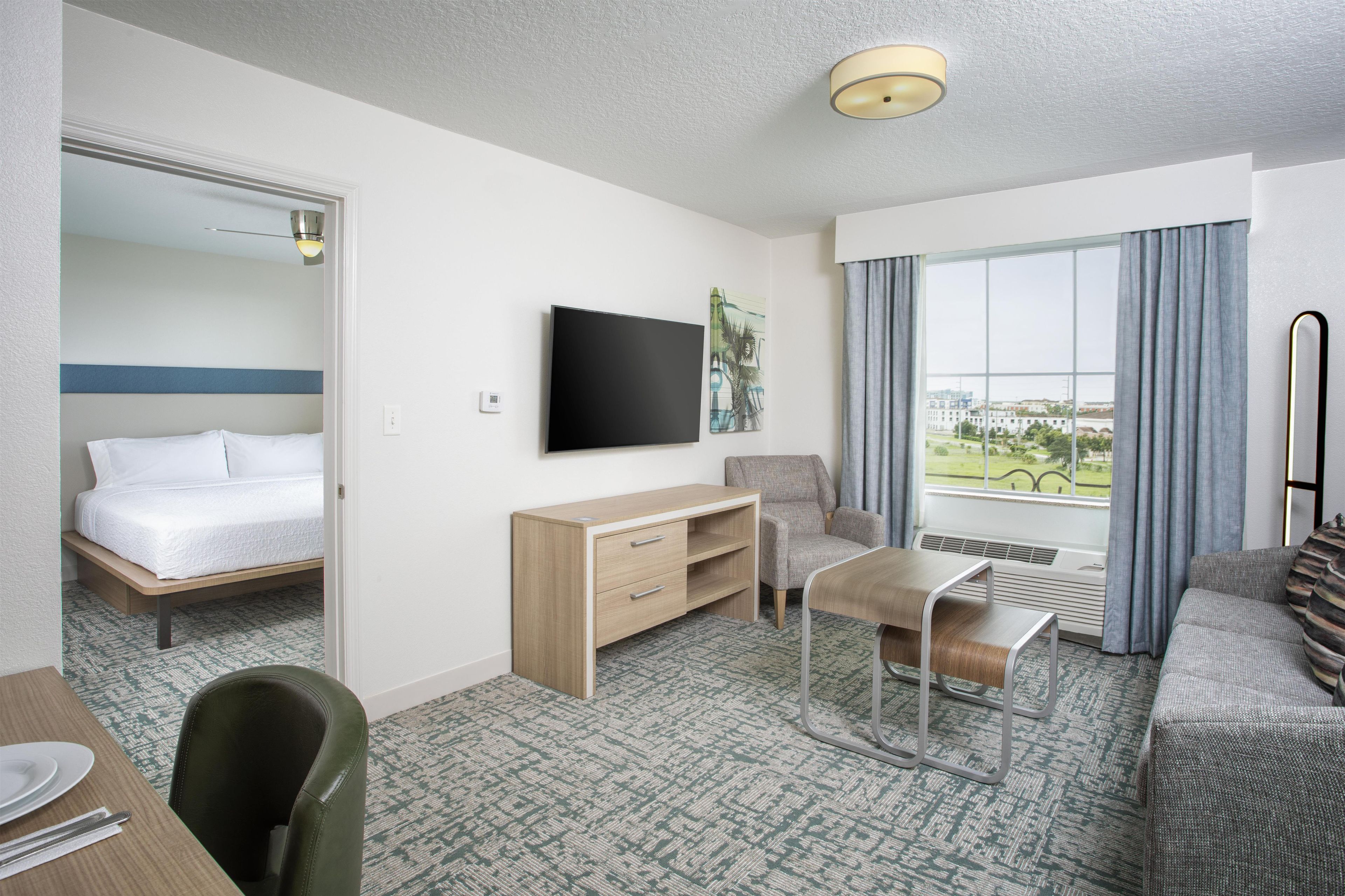 Habitación de hotel con cama, escritorio, silla, televisor y ventana con vistas.