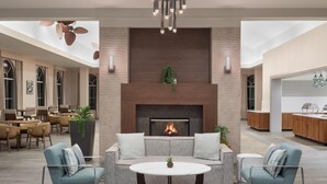 A modern living room with a fireplace, seating area, and a kitchen in the background. - Homewood Suites by Hilton Lake Buena Vista - Orlando (Orlando)