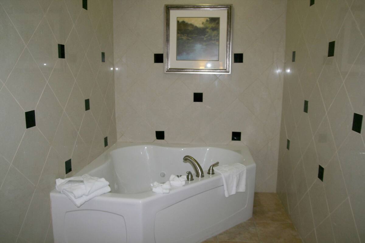 A bathroom with a large bathtub, a framed picture on the wall, and a tiled floor.
